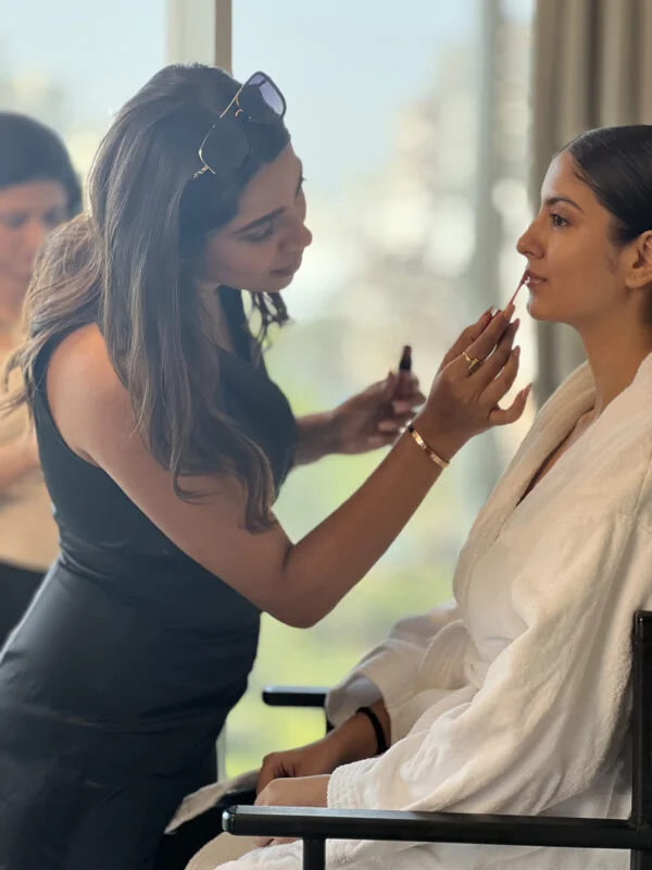 Makeup artist applying makeup to a client during a bridal makeup session.